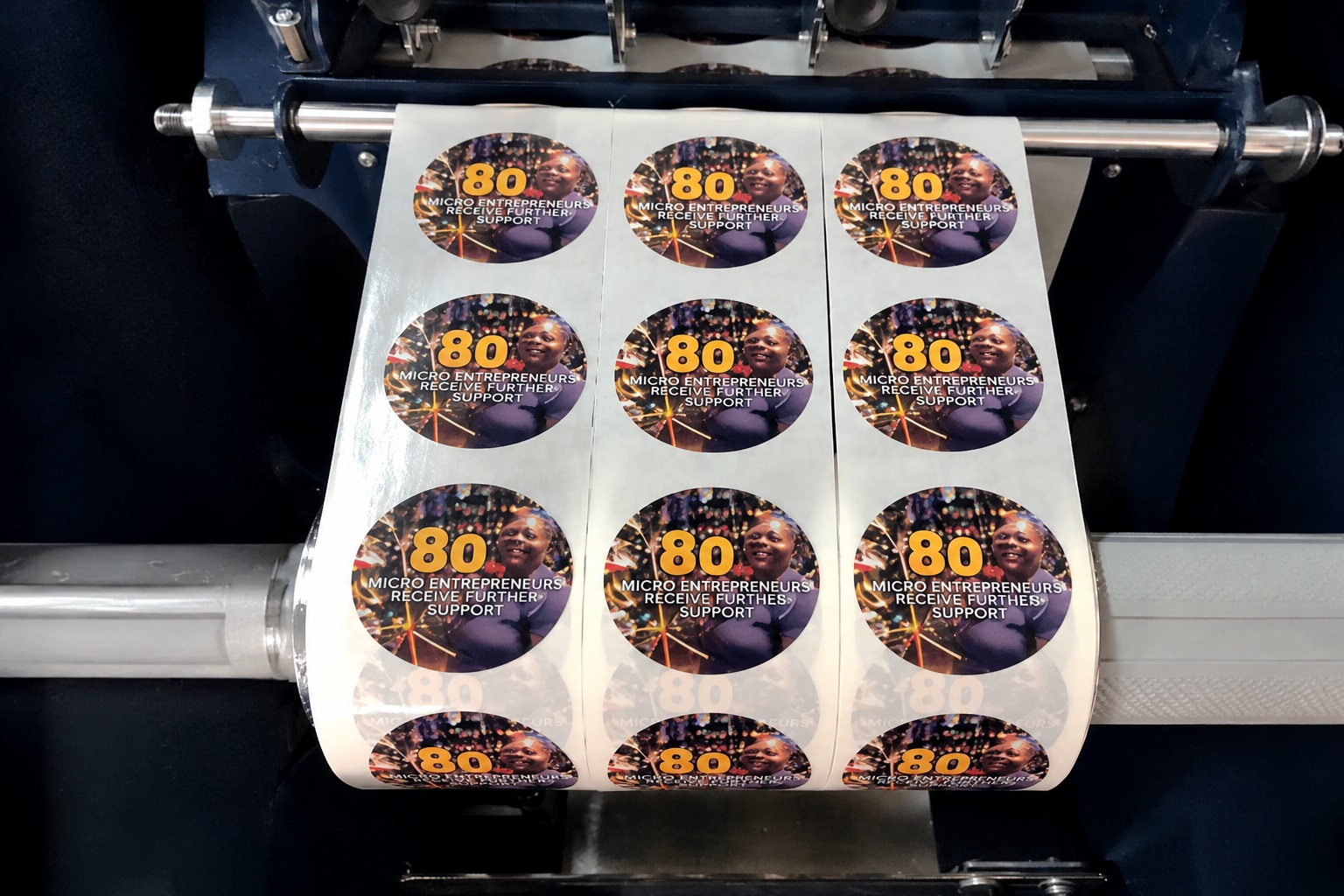 Circular custom labels running through printing and finishing equipment at Dynamic Signs & Print.